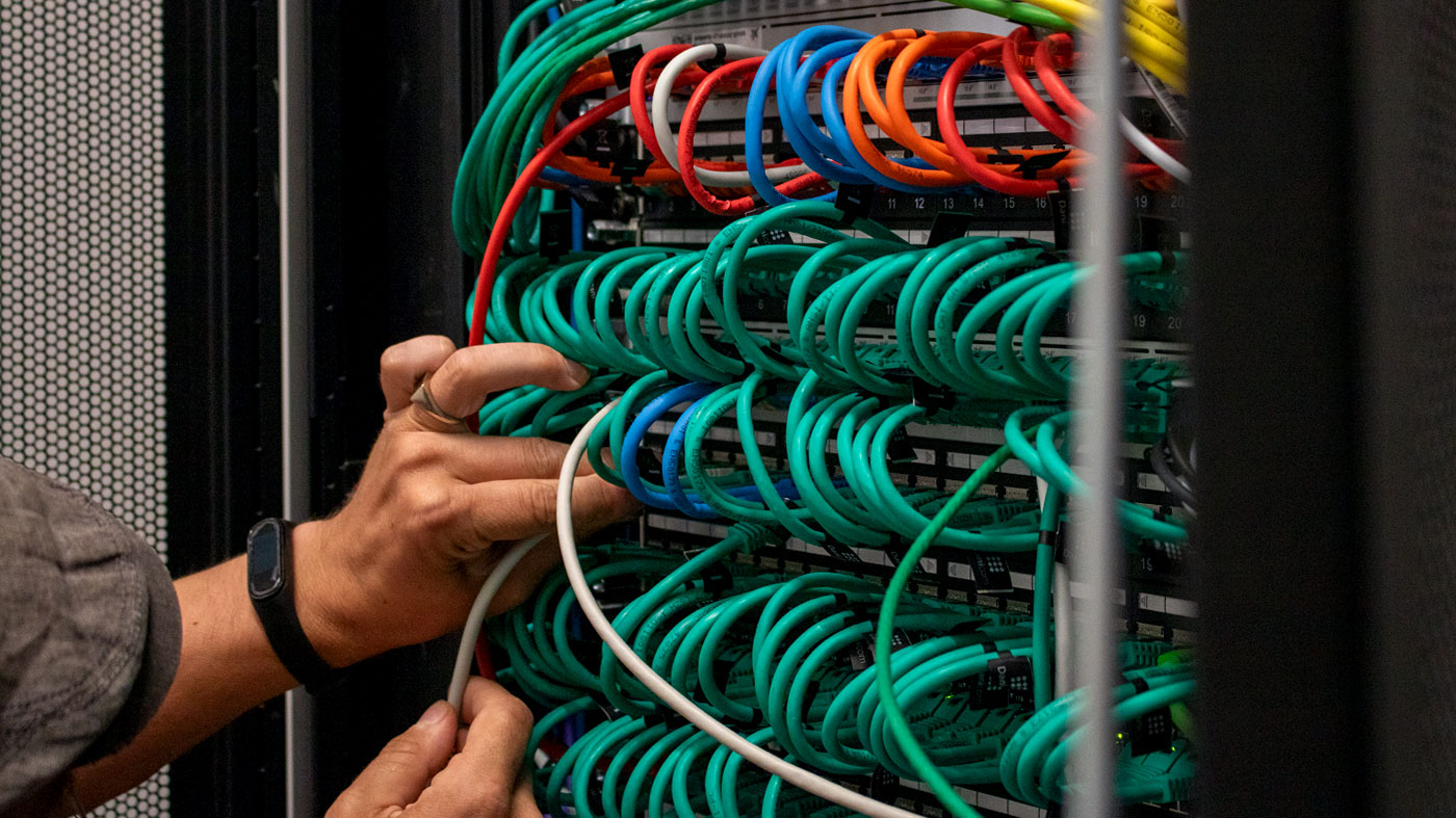 person with hat adjusting a multitude of cables on a server (Photo)